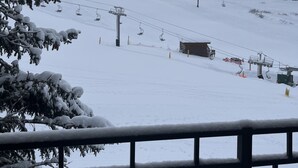 Un paysage de montagne enneigé avec des remontées mécaniques et un chalet.
