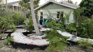 Una casa con jardín, patio y una silla azul.