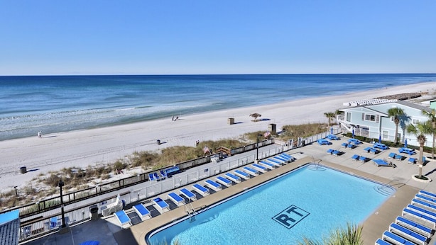 A pool area with lounge chairs and a view of the beach.