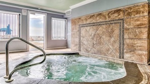 A spa area with a hot tub, tiled walls, and a view of the outdoors.