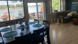 Un coin repas avec vue sur un lac, un salon avec un canapé et une lampe, et un ventilateur de plafond.