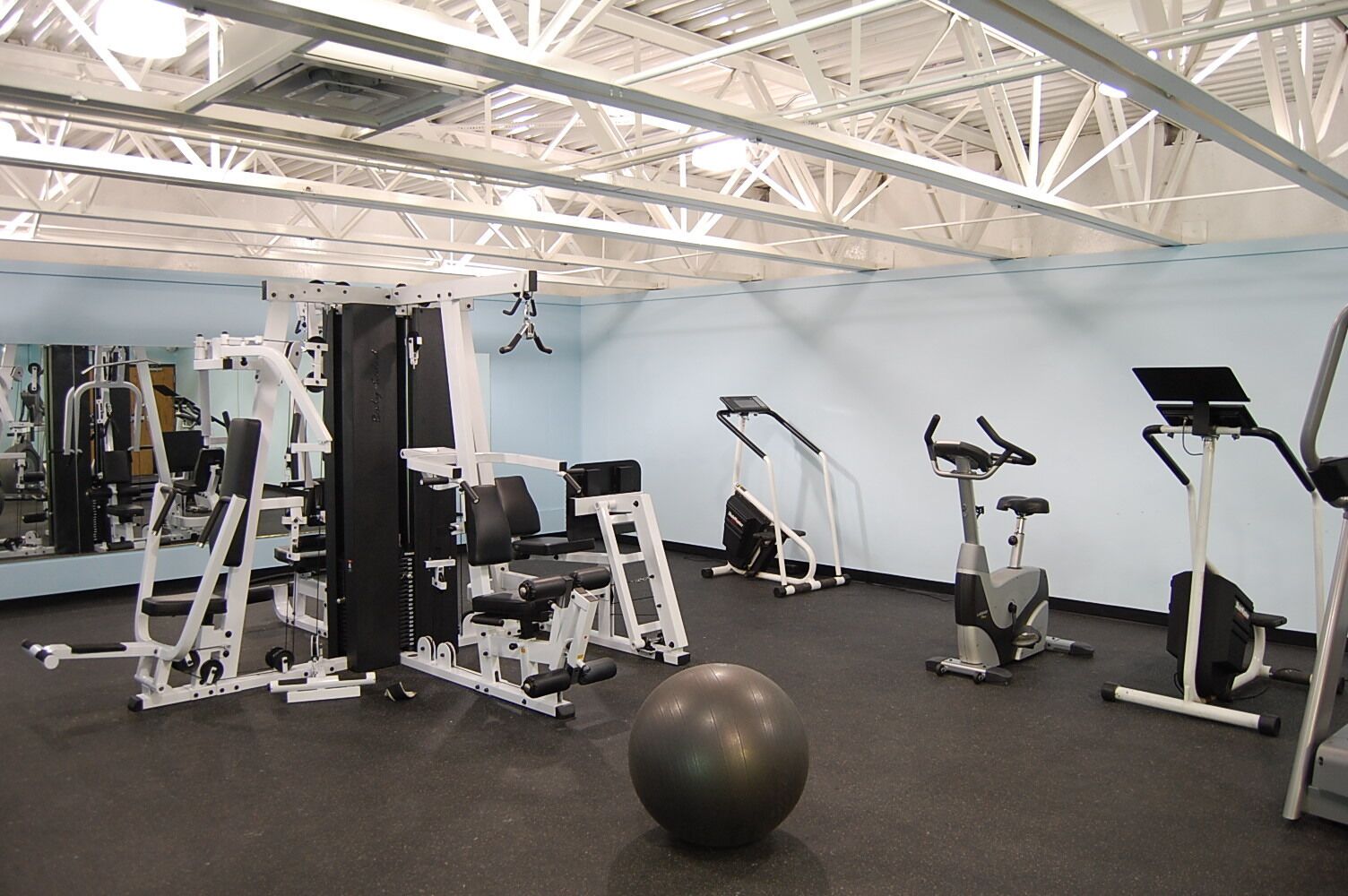 A gym with various exercise equipment, including treadmills, elliptical machines, and weight machines.
