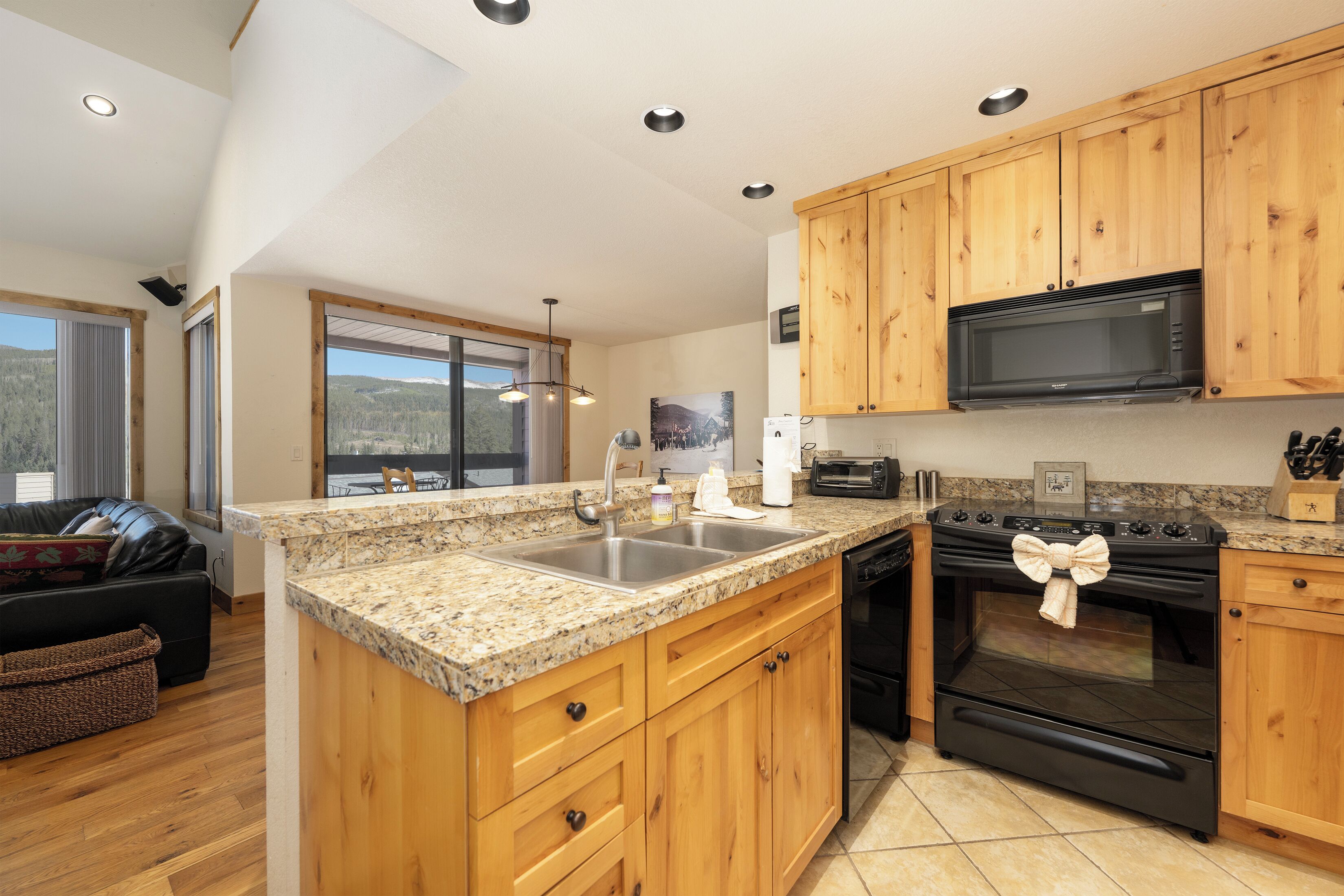 A modern kitchen with wooden cabinets, granite countertops, a built-in microwave, and a large island with a sink.