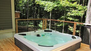 A hot tub on a wooden deck with a view of a forest. - Beautiful home in Picturesque setting just steps from Lake Michigan! (Fennville)