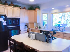 Kitchen features a central island, refrigerator, oven, microwave, and coffee maker.