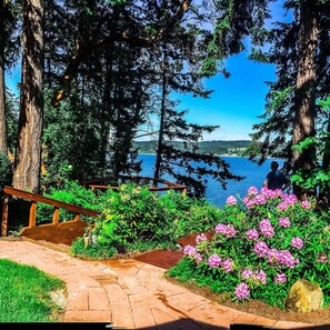 Surrounded by lush greenery and vibrant flowers, this serene outdoor space offers a tranquil view of the water.