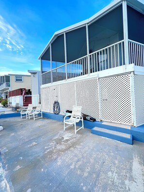 Un motel con un área exterior techada, un balcón con barandilla y algunas sillas para relajarse.