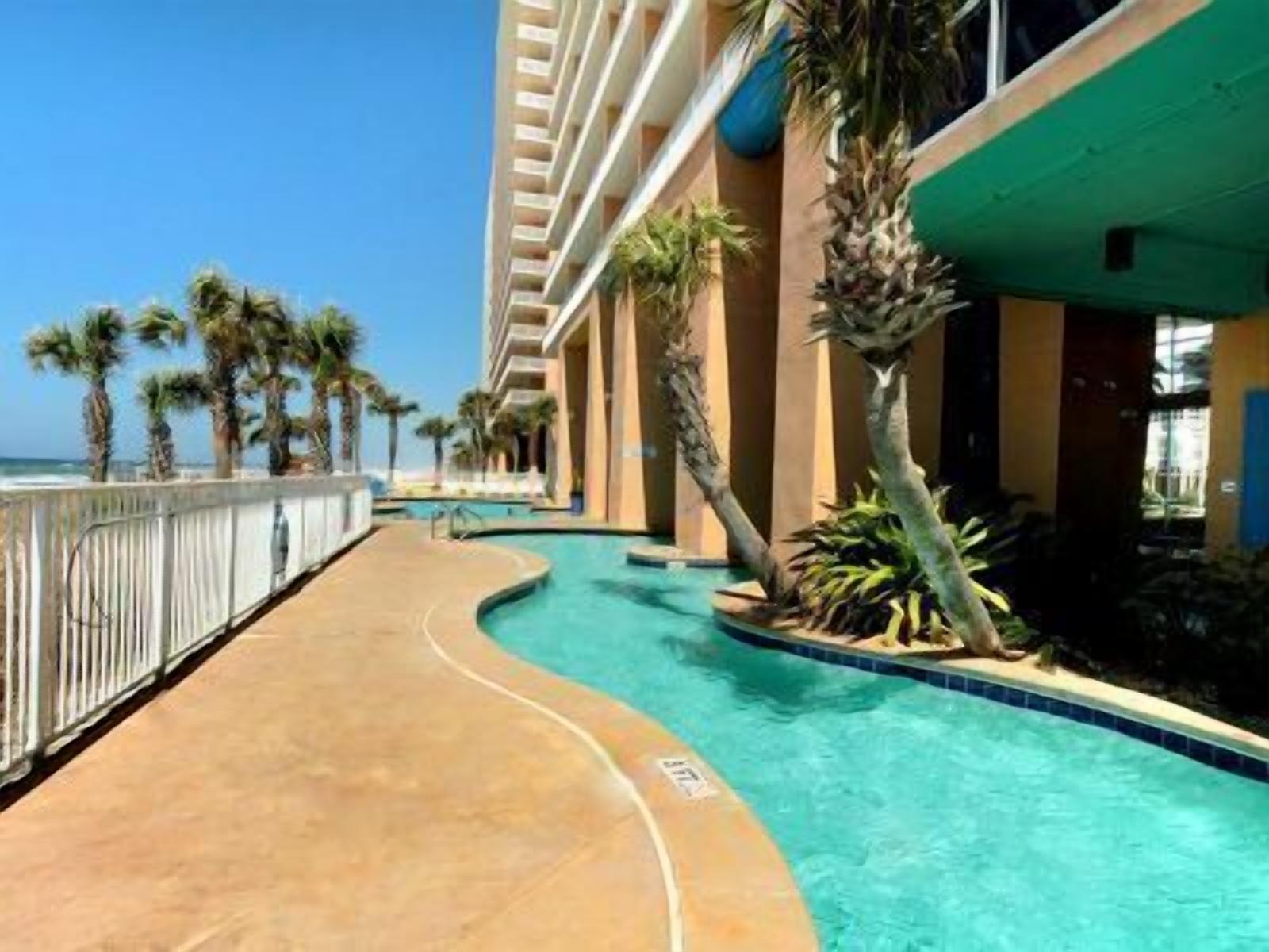 A pool area with a curved design, palm trees, and a building with balconies.