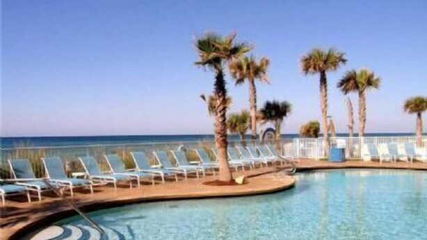 A poolside area with lounge chairs and palm trees, overlooking a clear blue body of water. - 4th Floor! ☼☼❀❀ 2BR/2BA,Sleeps 6,Handicap Acc,Living & Mstr Rms Facing The Beach (Panama City)