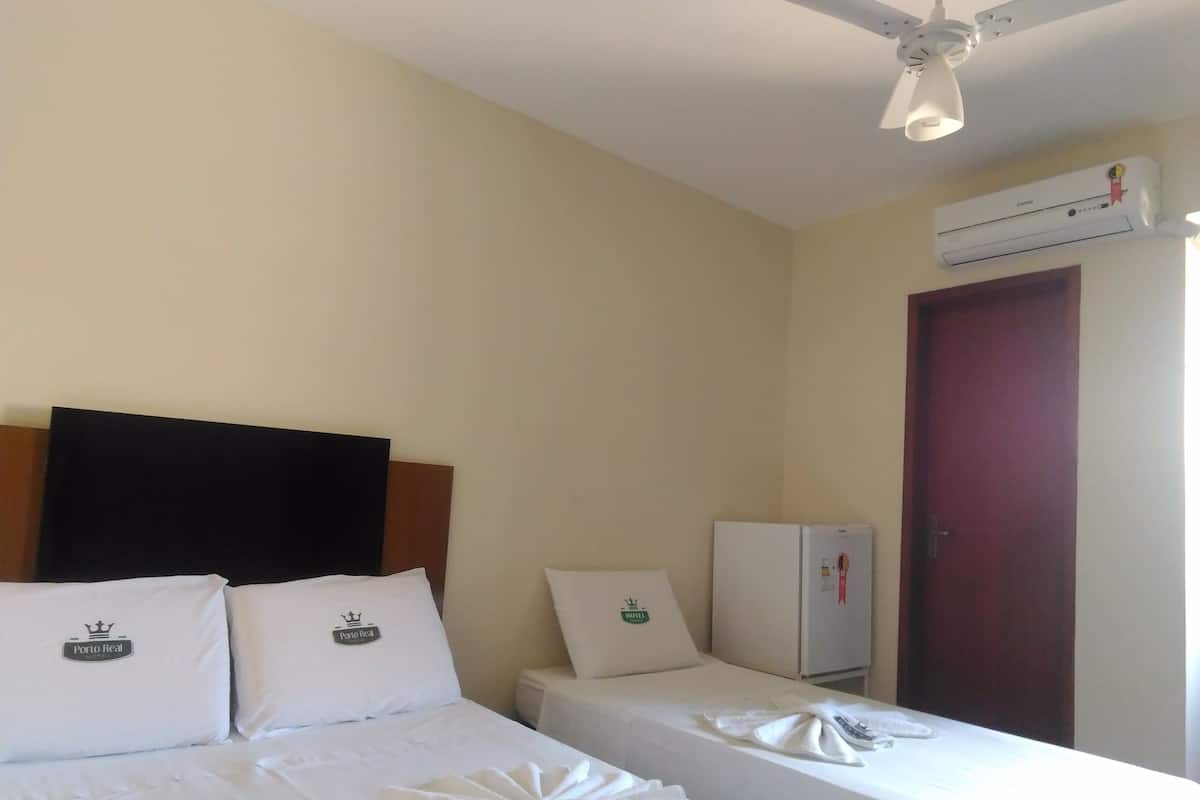 Quarto de hotel com duas camas, um ventilador de teto, ar condicionado e uma geladeira.
