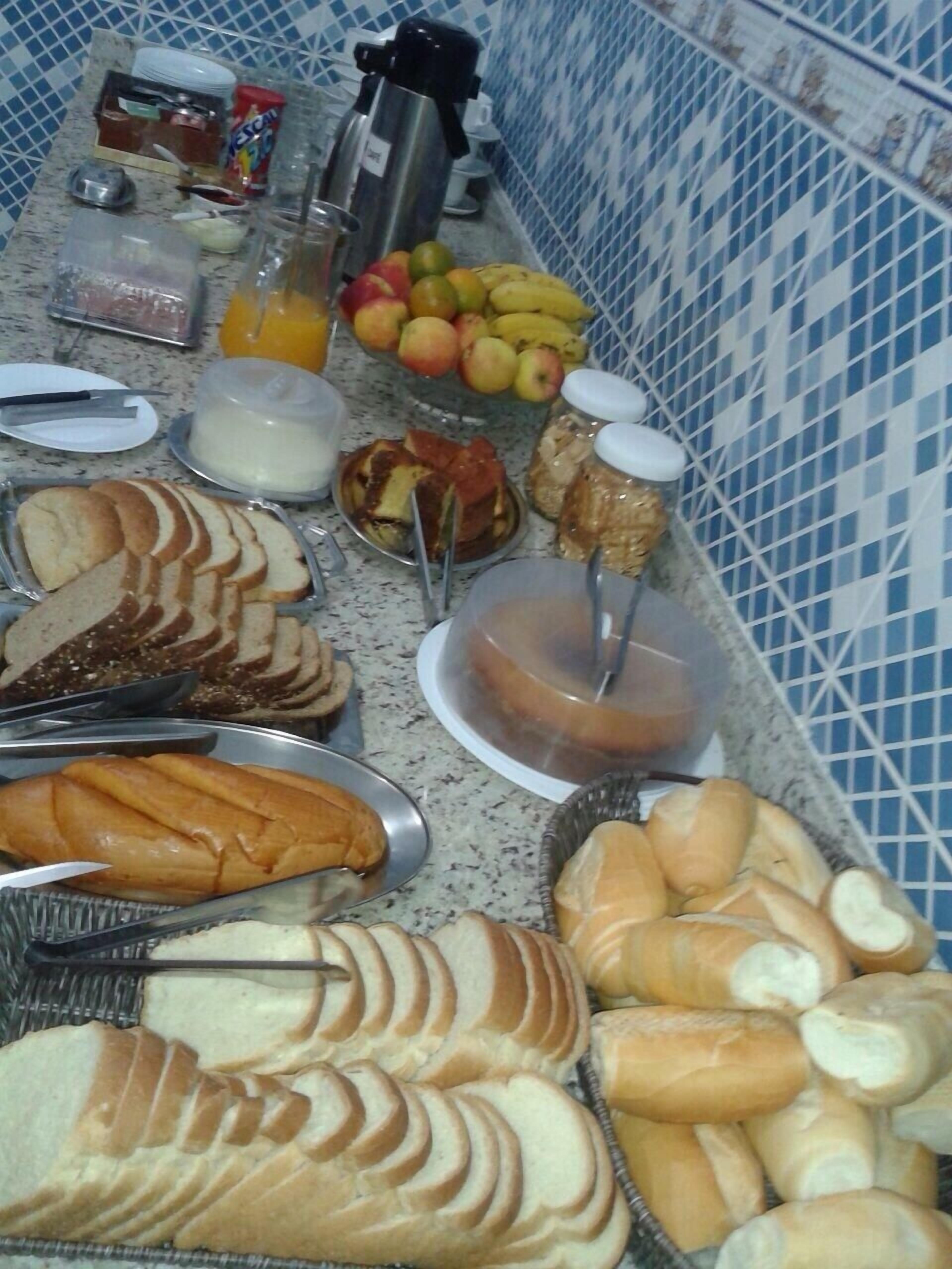Un bufé de desayuno con panes, bollería, frutas y bebidas variadas.