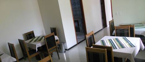 A dining area with multiple tables and chairs, a trash bin, and a television mounted on the wall.