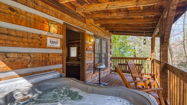 A wooden cabin with a hot tub, wooden deck, and outdoor seating. - Linger Longer 1607 - One Bedroom Cabin (Gatlinburg)