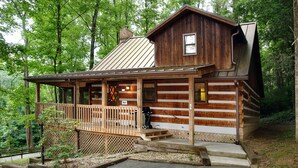 A rustic log cabin with a wooden porch, a metal roof, and a small deck area. - Parkside Party 1676 - One Bedroom Cabin (Gatlinburg)