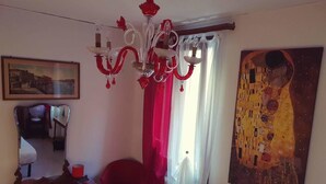 A room with a chandelier, a large painting, a chair, and a radiator. - Casa Di Adel (Venice)