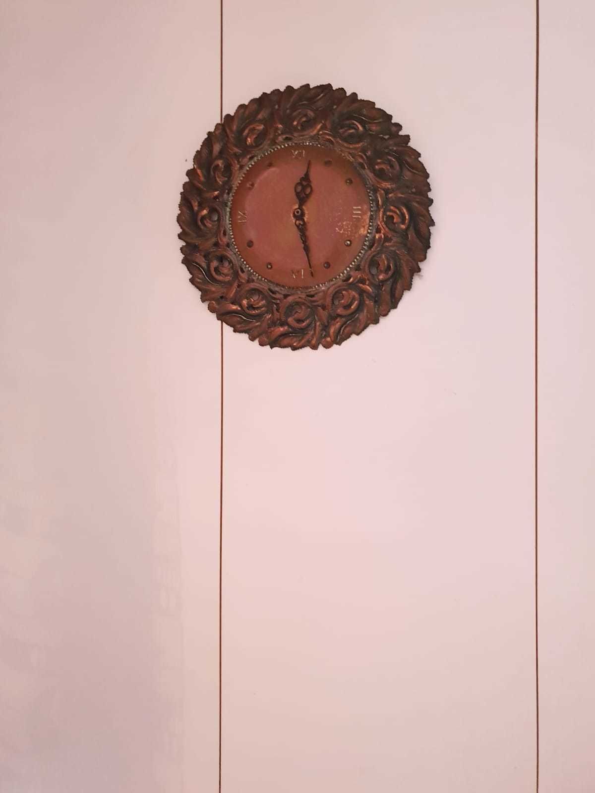 A wall-mounted clock with an ornate, circular frame.