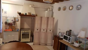 A compact kitchen with a stove, oven, and wooden cabinets. - Casa Di Adel (Venice)