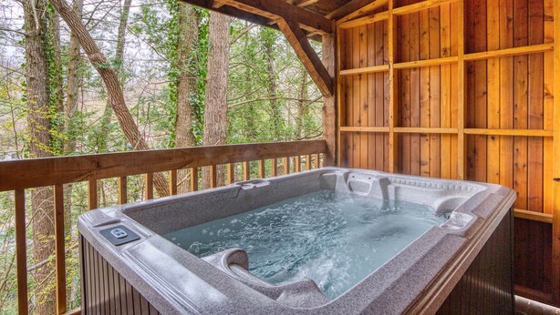 A hot tub in a wooden cabin with a wooden deck and a forest view. - Leather And Lace 1615 - One Bedroom Cabin (Gatlinburg)