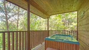A wooden deck with a hot tub and a bench, surrounded by trees. - Dream Maker 120 - One Bedroom Cabin (Sevierville)