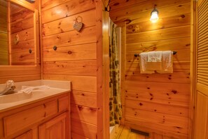 A wooden cabin bathroom with a sink, mirror, towel rack, and shower curtain.