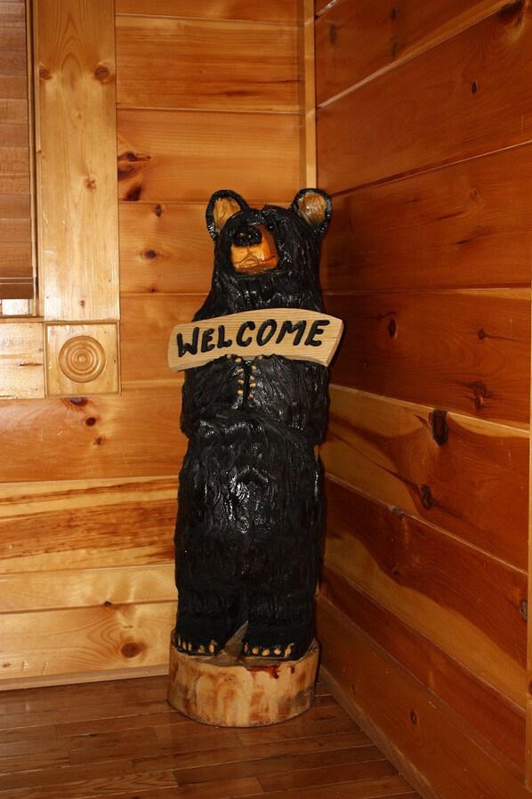 Une statue d'ours en bois avec une pancarte indiquant « BIENVENUE ».