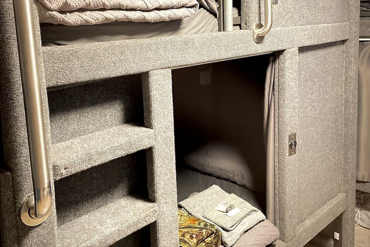 A bunk bed with a ladder, a small shelf, and a door with a handle.