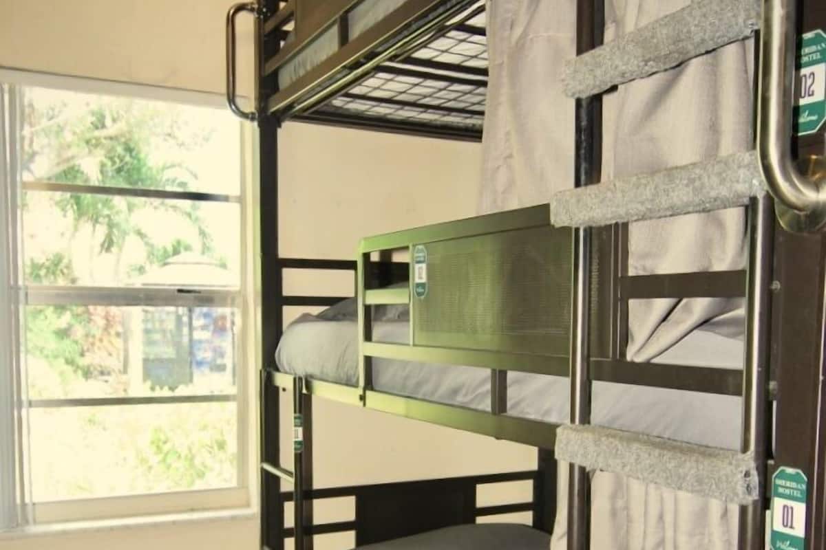 A bunk bed room with a window, a small stool, and a mat on the floor.
