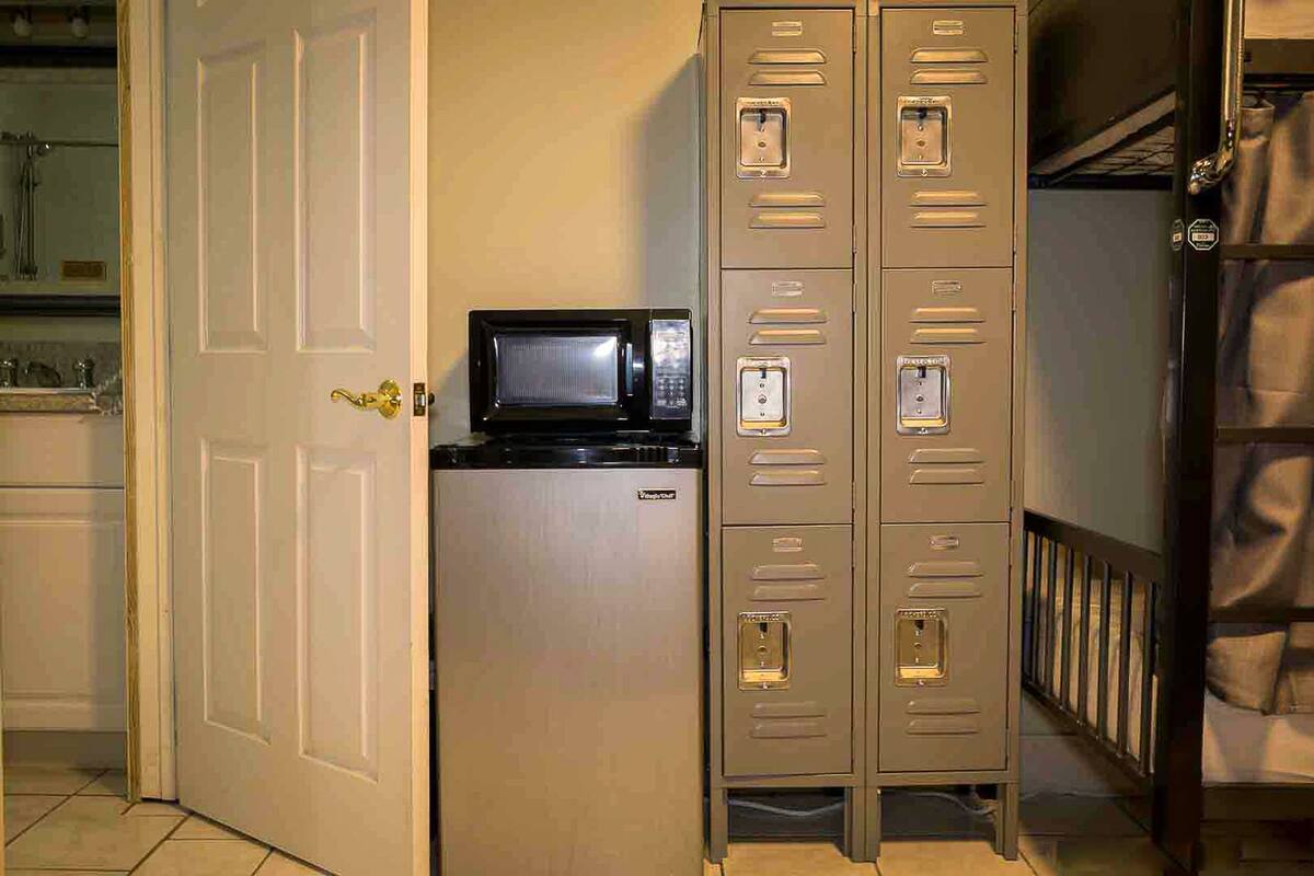 A kitchenette with a microwave, a white door, and a set of metal lockers.