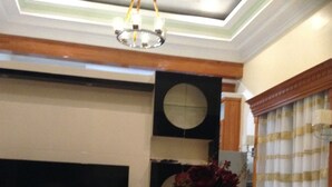 A living room with a flat-screen TV, a glass coffee table, and a vase with flowers. - DanSam House (Davao)