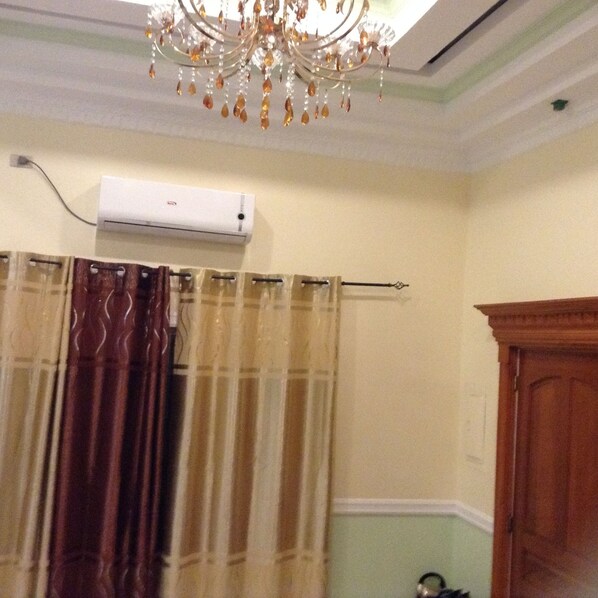 A bathroom with a shower curtain, an air conditioning unit, and a wooden door.