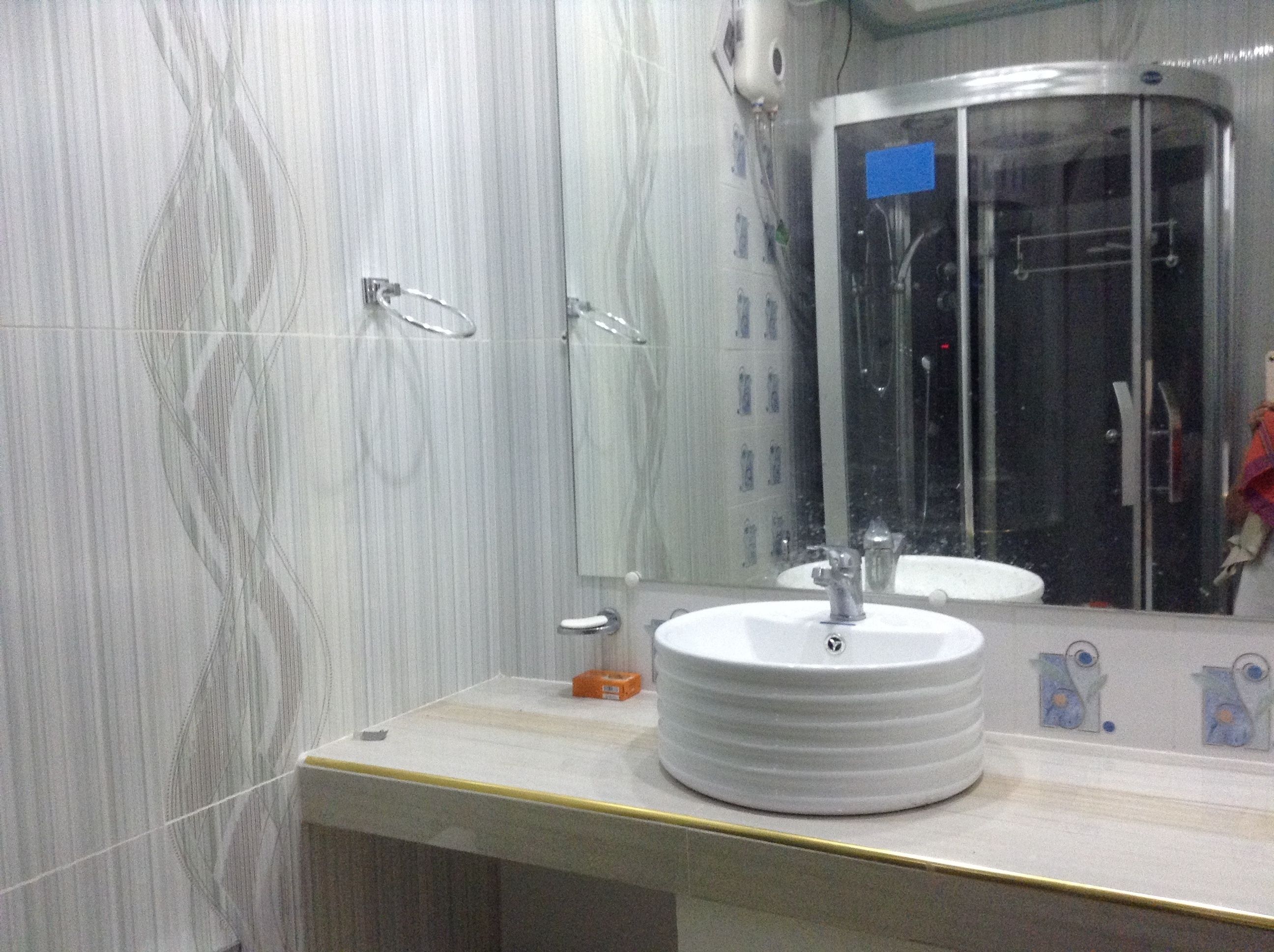 A bathroom with a round sink, a mirror, and a shower area.