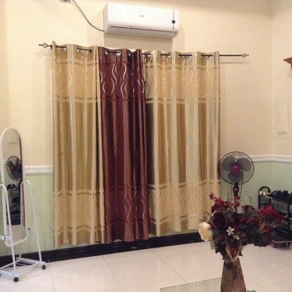 A room with a curtain, a fan, and a flower vase. - DanSam House (Davao)