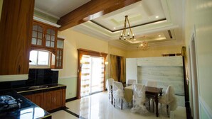 A spacious dining area with a large table and chairs, wooden cabinets, and a chandelier. - DanSam House (Davao)