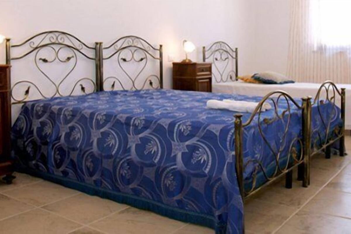 Un dormitorio con una cama grande, dos mesitas de noche, una mesita pequeña y una silla.
