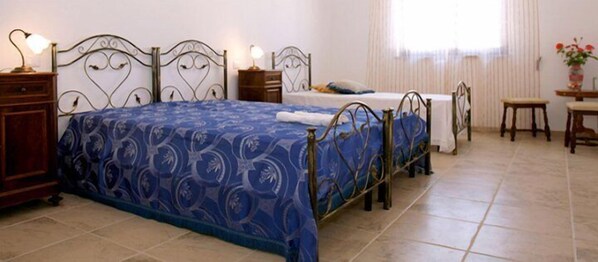 A bedroom with a large bed, two bedside tables, a small table, and a chair.