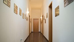A hallway with wooden flooring, white walls, and framed pictures on the walls. - B&B Li Cuti (Tiggiano)