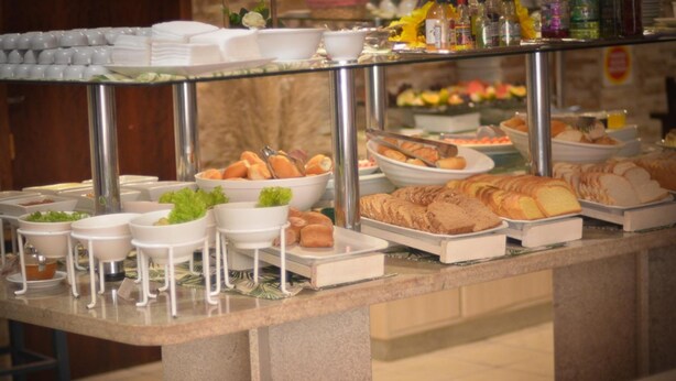 A buffet with various food items and condiments. - Residencial Baleia Franca (Florianópolis)