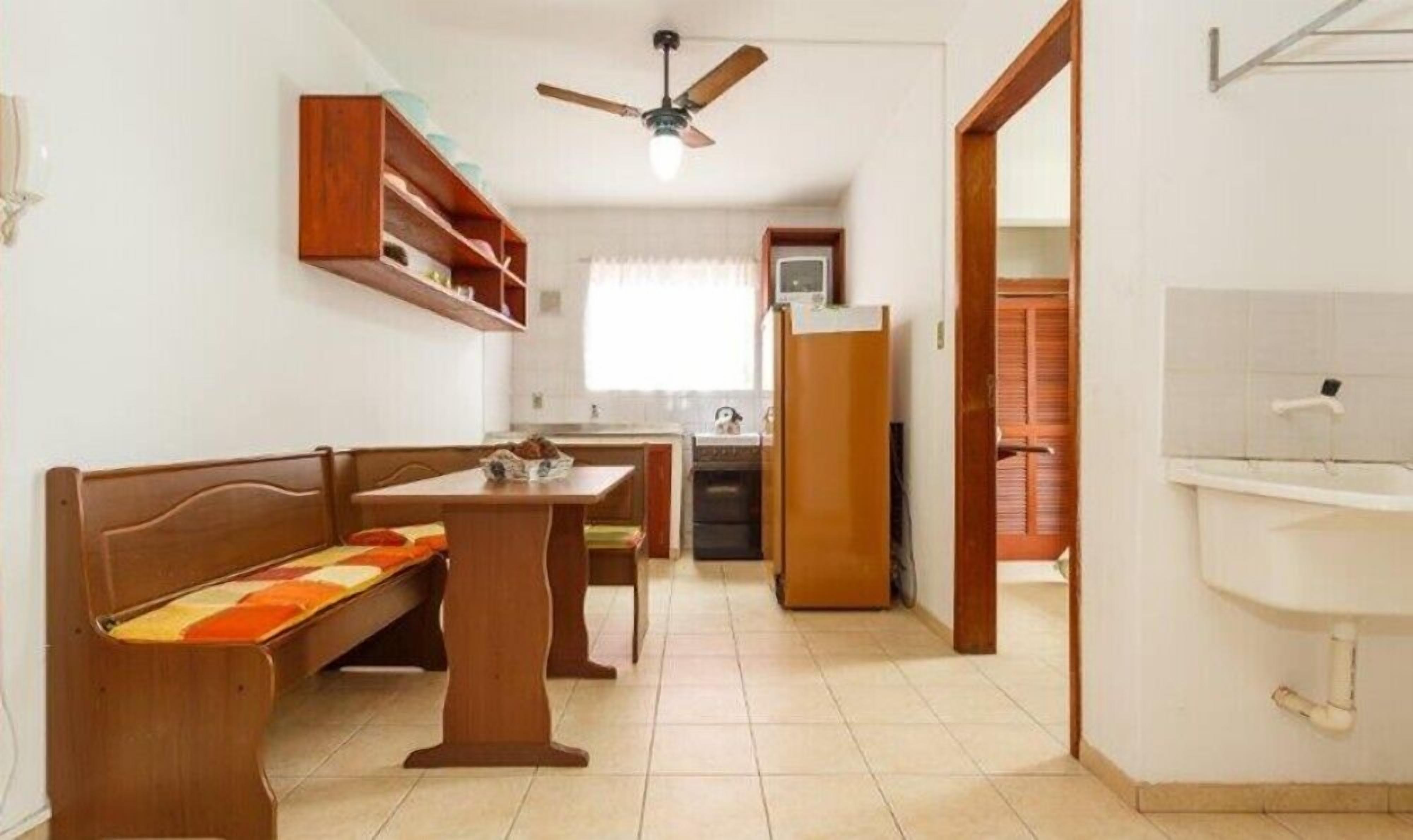 A compact kitchen with a dining area, a ceiling fan, and a visible bathroom.