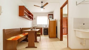 A compact kitchen with a dining area, a ceiling fan, and a visible bathroom. - Residencial Buenos Aires (Florianópolis)