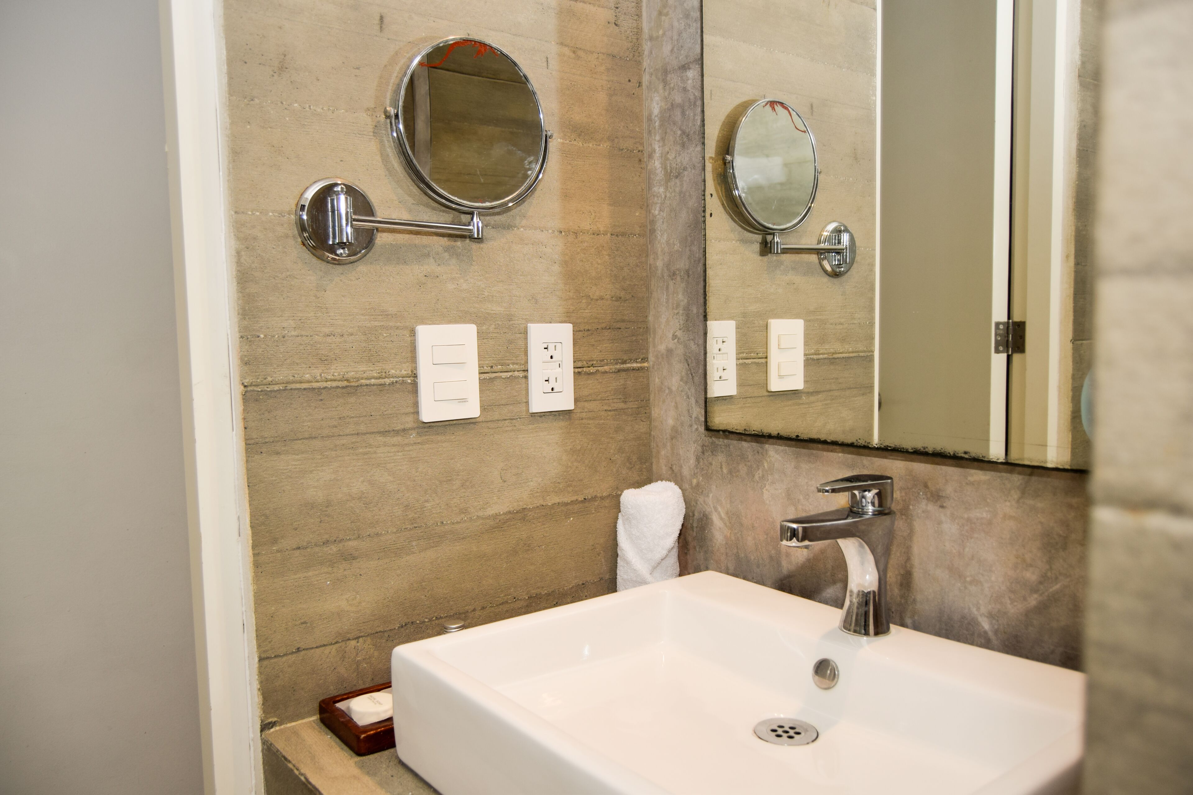 Un baño con un espejo grande, un lavabo y dos luces empotradas.