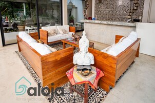 Un moderno espacio de sala con muebles de madera, una estatua decorativa y una alfombra estampada.