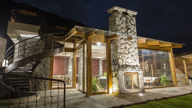 Una casa moderna con camino in pietra, scala a chiocciola e veranda vetrata.