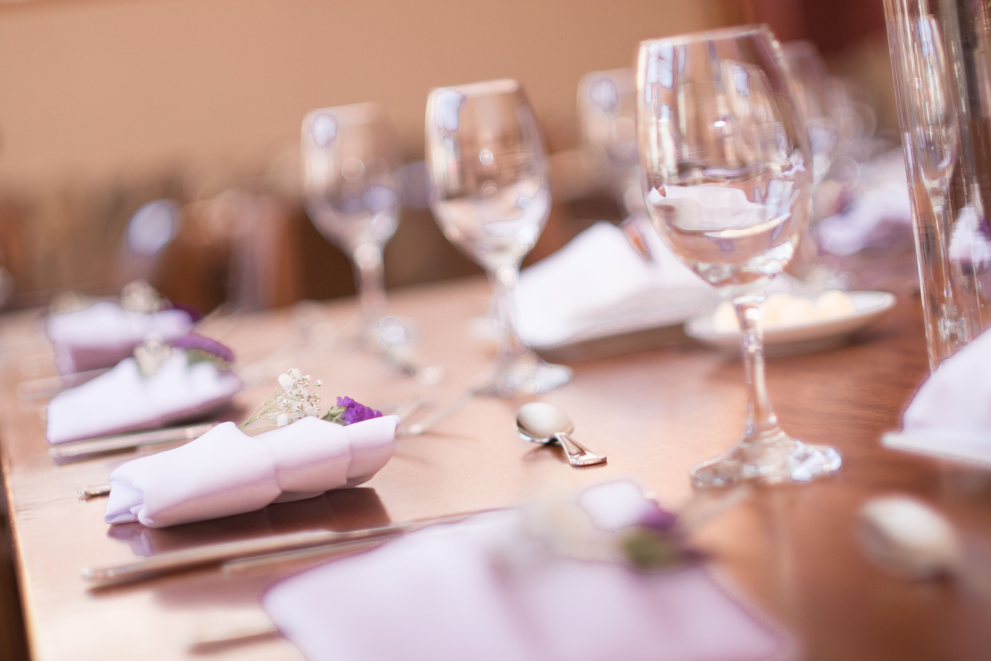 A table set with wine glasses, plates, and folded napkins.