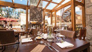 Un ristorante con parete in pietra, travi in legno e vista sull'esterno.
