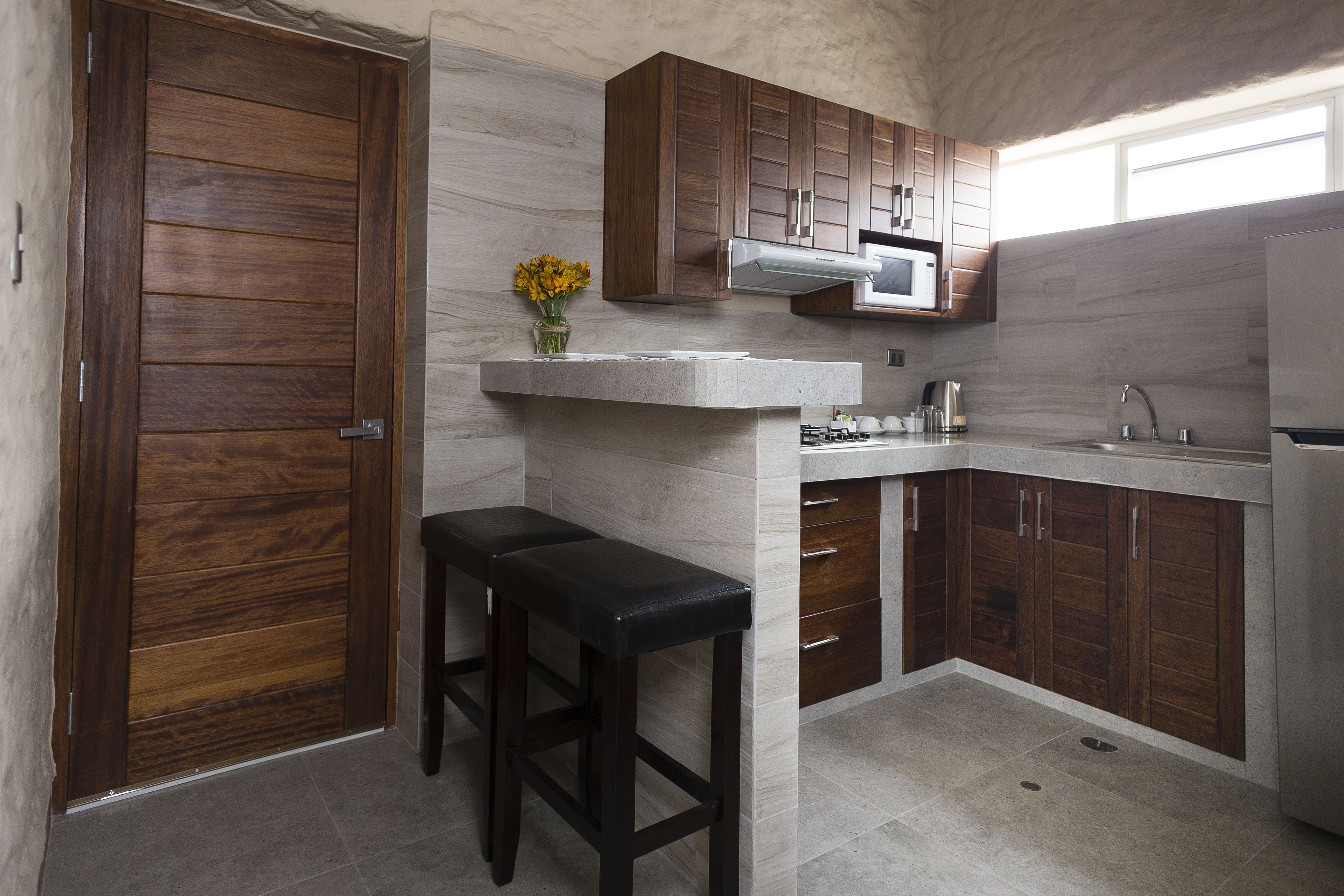 A kitchen with wooden cabinets, a microwave, a sink, and a bar stool.