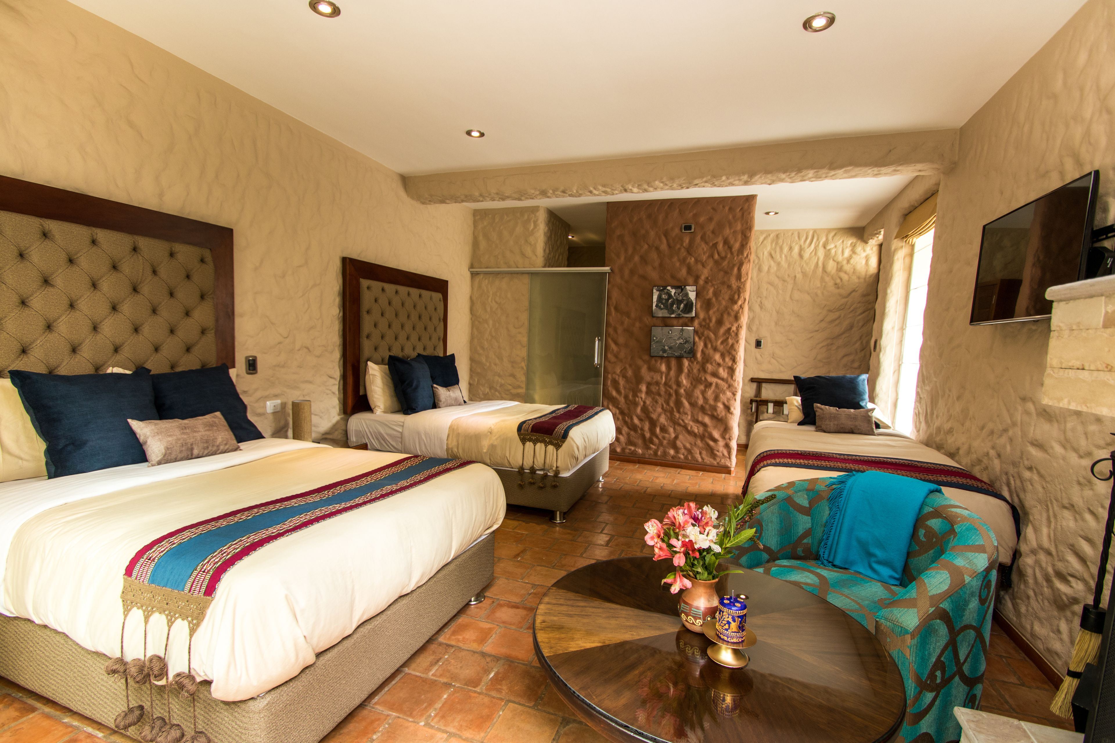 A hotel room with two beds, a sofa, a coffee table, and a TV.