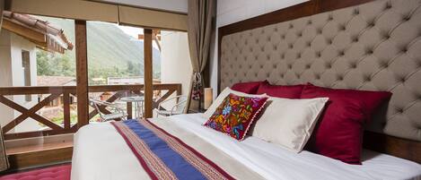 A bedroom with a large bed, a view of the outdoors, and a balcony.