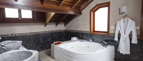 Un baño moderno con una bañera independiente, lavamanos de piedra y un ventanal amplio.