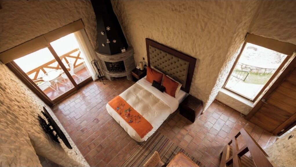 Un dormitorio con techos altos, una cama grande, una chimenea y dos ventanas que ofrecen luz natural.
