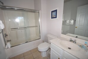 Ein Badezimmer mit Duschkabine, Toilette, Waschbecken und einem gerahmten Bild an der Wand.